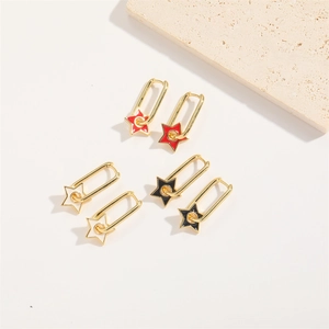 Detailed close-up of three pairs of star earrings in red, white, and black with gold frames