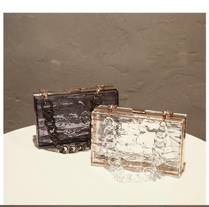 Nahaufnahme von gewellten Acryl-Clutches in Transparent und Rauchgrau mit Goldkette