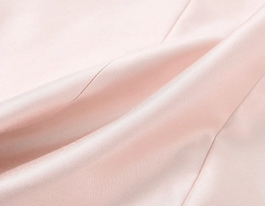 Détail du tissu en satin rose montrant une texture lisse et un éclat nacré doux
