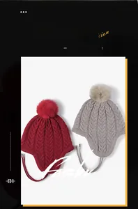 Close-up of thick knit trapper hats with faux fur pom-poms and braided earflap straps