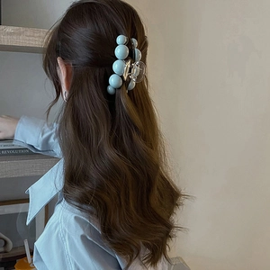 Détail d'une pince à cheveux en perles bleu clair sur un modèle, accessoire élégant