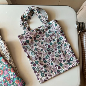 Detailed view of floral cotton tote bags with copper snap buttons and hand straps
