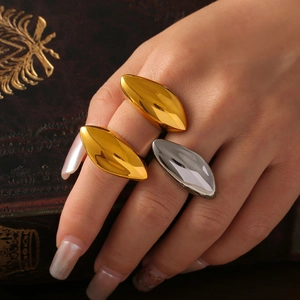 Minimalist olive-shaped gold and silver titanium steel rings shown on a vintage book