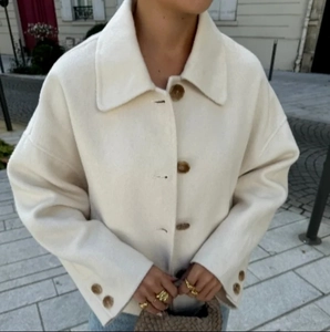 Close-up of off-white wool-like jacket featuring wide lapels and brown buttons