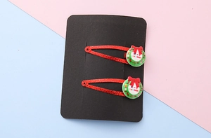 Detail of glittery red Christmas tree hair clips with green festive wreath decorations