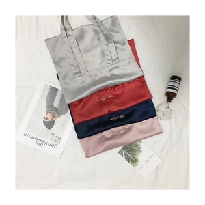 Detail of satin shoulder bags in four colors with Not Your Babe embroidery