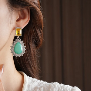 Détail de boucles d'oreilles vintage style palais avec goutte émeraude et halo de cristal