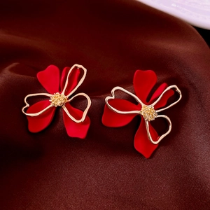 Detailed close-up of red and gold floral vintage stud earrings on a dark silk fabric