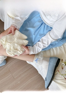 Detail of ballet style lace socks with blue bow and vertical knit texture in cream