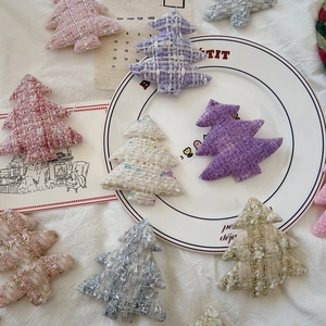 Flat lay of tweed Christmas tree ornaments in various pastel colors on a white fabric base