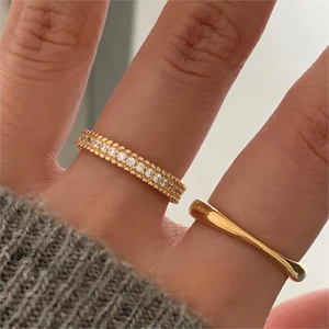 Macro shot of gold eternity ring with zircons and minimalist open ring on finger