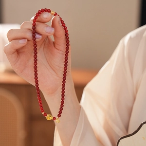 Détail d'un bracelet en perles d'agate rouge avec des accents plaqués or 18 carats