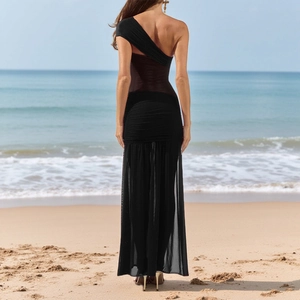 Detail of elegant black one-shoulder dress with mesh splicing and mermaid hem at beach