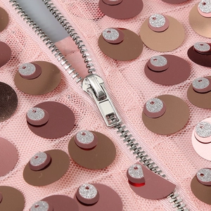 Détail d'une robe rose à paillettes avec sequins multicolores et fermeture éclair en métal