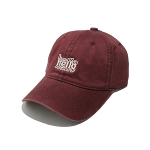 Detailed embroidery of white Hello text on burgundy cotton canvas baseball cap surface