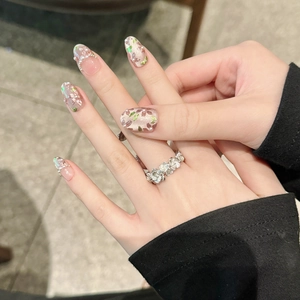 Detail of floral press-on nails with cat-eye pearls and a matching flower ring
