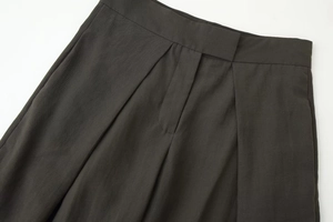 Vue détaillée du pantalon plissé gris foncé montrant la taille et la texture du tissu sergé