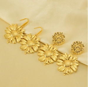 Detailed view of sunflower stud earrings with hammered gold texture on silk background