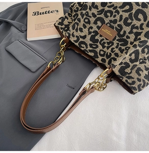 Detail of leopard print tote bag with metal chain strap and brown leather patch