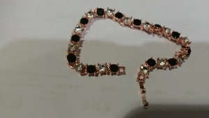 Détail d'un bracelet tennis or rose avec alternance de gemmes noires et blanches