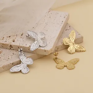 Elegant gold and silver titanium butterfly earrings displayed on natural stone