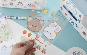 Hand holding waterproof cartoon PET stickers featuring cute bears and rabbit motifs