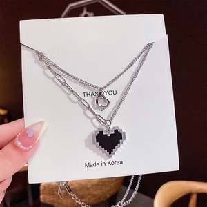 Détail du collier argenté à double épaisseur avec pendentifs cœur pixel et évidé