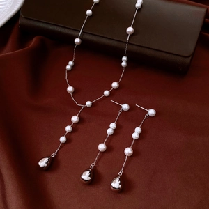 Detail of vintage pearl necklace and teardrop earrings set on premium silk background