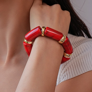 Detail view of red acrylic marble beads and gold metallic spacers on a flexible bracelet