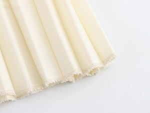 Detail of cream pleated fabric texture with elegant metallic sheen and raw edge finish