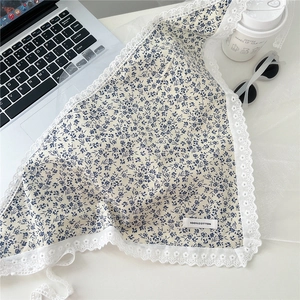 Flat lay of floral cotton scarf with lace trim and 100% cotton tag in lifestyle setting