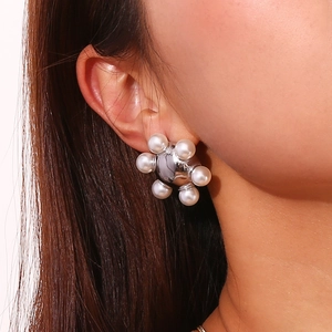 Close-up of elegant wheel-shaped earring with white pearls and a silver metal sphere