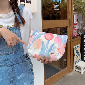 Floral canvas makeup bag with tulip print and zipper closure held by model in cafe setting
