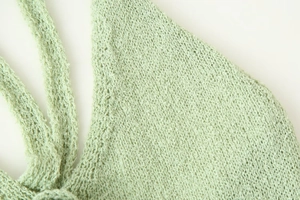Detailed macro view of light green knit texture and intricate crochet craft on summer dress