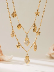 Detail of bohemian gold layered necklace with heart, star, and religious coin charms