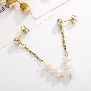Détail de boucles d'oreilles pendantes dorées avec perles blanches et strass brillants
