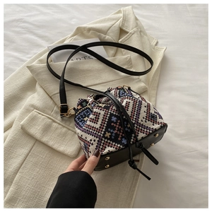 Ethnic style bucket bag with colorful geometric patterns on a beige blazer background