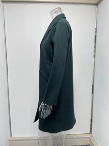 Detail view of dark green wool coat featuring side pockets and notched lapel finish
