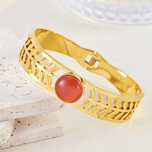 Detailed close-up of golden hollow bracelet featuring a central reddish-brown cat eye stone