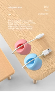 Detailed view of pink and blue silicone cable organizers on a light wood desk surface
