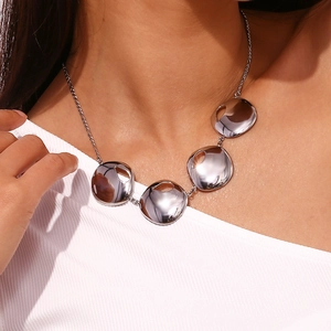 Close-up of polished silver water drop pendants on a minimalist stainless steel chain