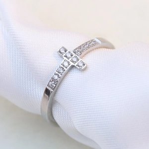 Macro detail of silver cross ring featuring sparkling cubic zirconia on textured fabric