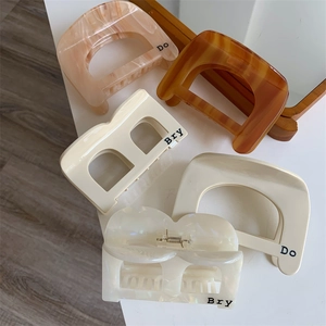 Collection of large acetate claw clips in beige and tortoiseshell on a white surface