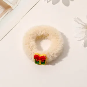 Close-up of plush beige Christmas hair scrunchie with festive yellow gift box charm