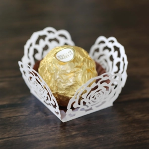 Detail of white laser-cut rose lace candy cups for wedding chocolate decoration