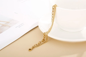 Close-up of golden double-layer heart shell bracelet hanging on a white ceramic cup