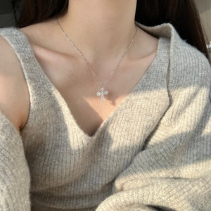 Detail of a silver zircon-inlaid cross necklace worn by a model in natural light