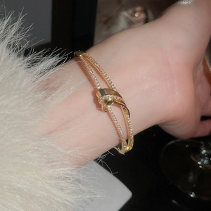Détail d'un bracelet torsadé doré serti de zircons sur une manchette en peluche