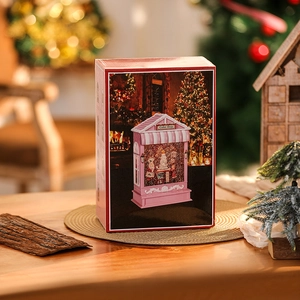 Detail of a warm glowing Christmas candy house music box with a pink cake shop scene