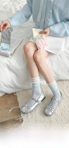 Close-up of pastel ribbed crew socks worn with silver Mary Jane shoes in a soft setting